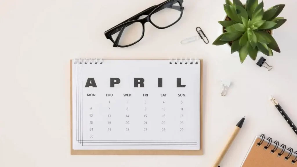 imagem mostrando um calendario do mes de abril (april) com um oculos em cima, lapis, caderno e uma plantinha